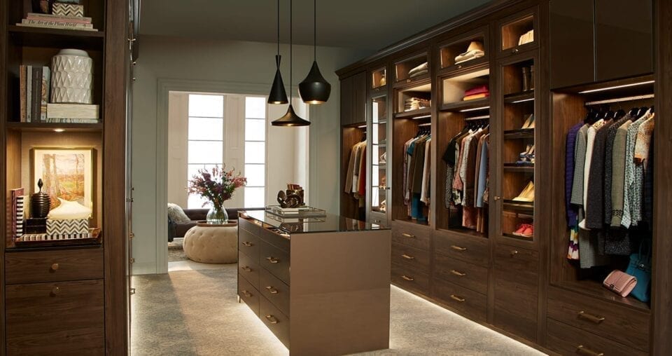 walk in closet in dark wood finish with island in the middle