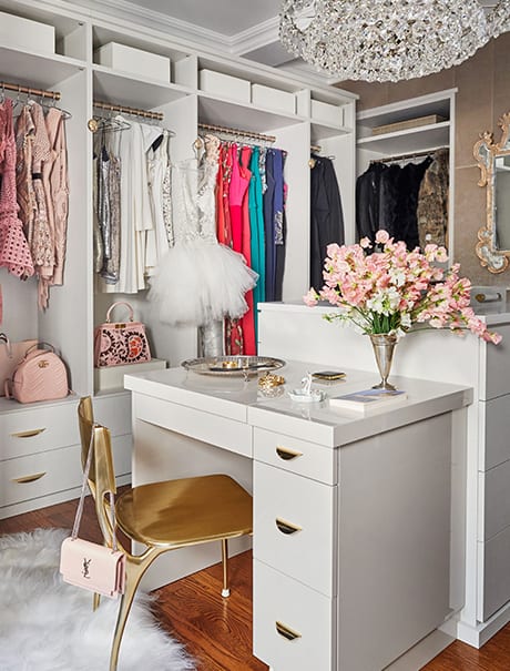 White luxurious walk-in closet with center desk and gold chair