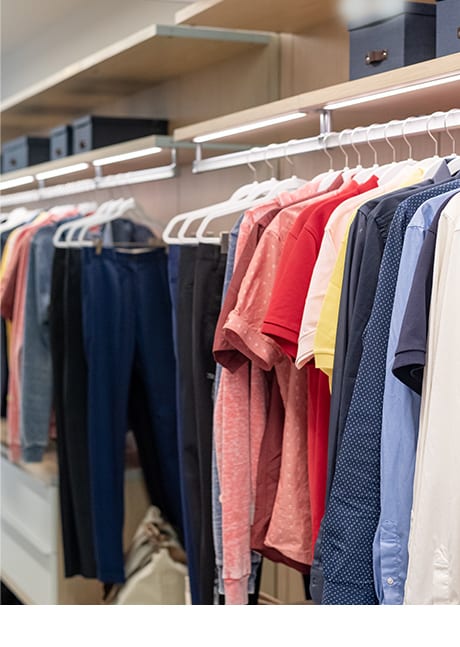Colored shirts and pants hanging from white hangers