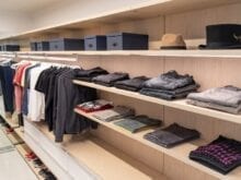 Folded mens shirts and show boxes lined up on tan virutoso shelves