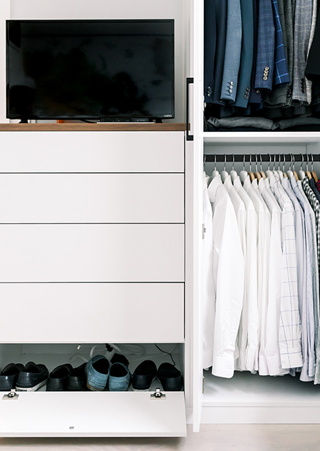 Custom white dresser and custom white closet with clothing on hanging pole
