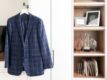 Blue suit on rod in front of white two door custom closet and custom storage shelfs