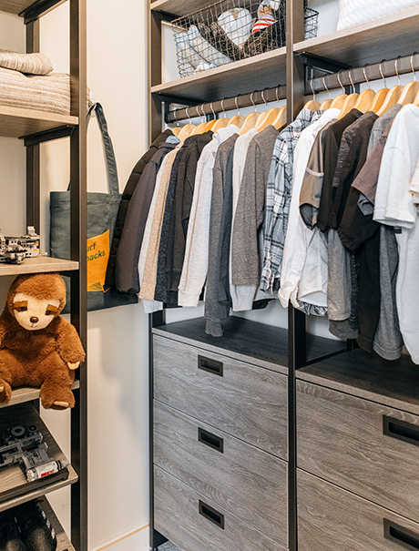 Custom walk-in closet with grey dressers and a custom rack