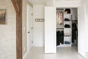 Custom white reach in closet with a shelving system and clothing rod