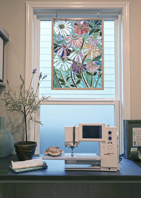 Zona de trabajo personalizada con una pieza de arte floral en vidrio y una máquina de coser