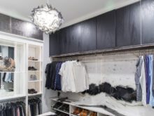 Custom white walk in with a grey trim ceiling light and a custom clothing rod with cabinets above