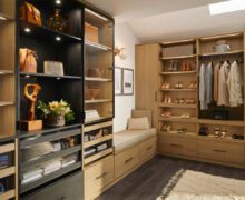 Custom LED lighting in a walk in closet in natural wood grain finish by California Closets