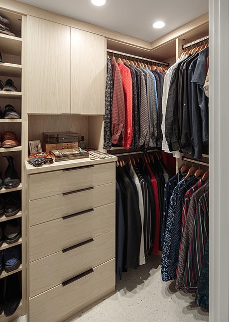 Walk in closet with custom dresser and built in shoe rack in a light wood finish with metal hardware