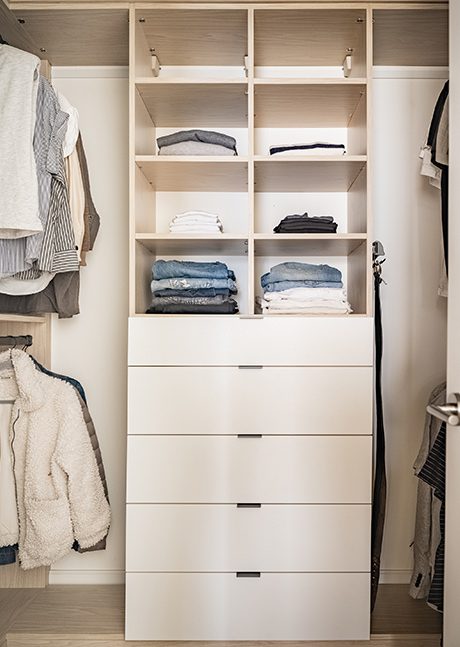 Closet organization in a walk in with custom shelves, drawers and hanging poles for wardrobe created by California Closets
