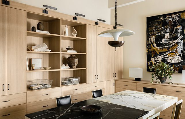 La oficina personalizada del diseñador de interiores Jeremiah Brent, diseñada con armarios, estanterías y cajones en un acabado de madera clara veteada por California Closets.