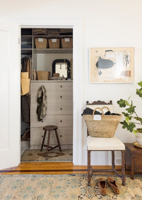 Un vistazo al vestidor con acabado de madera, estanterías y ropa colgada creado por California Closets.