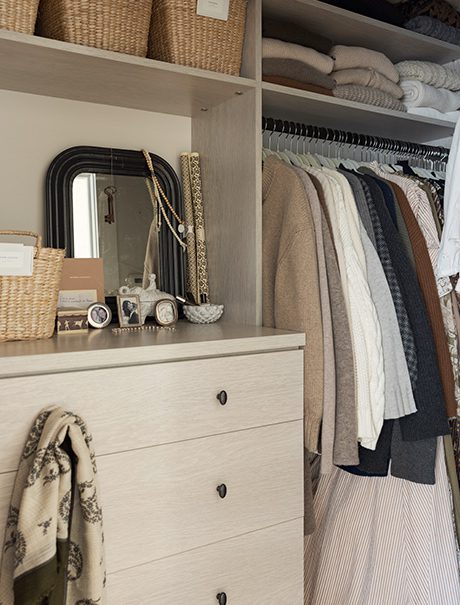 Walk in closet organization with shelving, built in dresser and hanging rods for clothes in light wood finish by California Closets