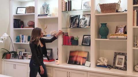Charissa Thompson’s custom-built library with open shelving, LED lighting and custom cabinets in a light wood grain finish created by California Closets