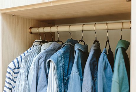 Almacenamiento para calzado personalizado y cubículos para suéteres y accesorios en un vestidor con acabado de madera veteada blanca creado por California Closets