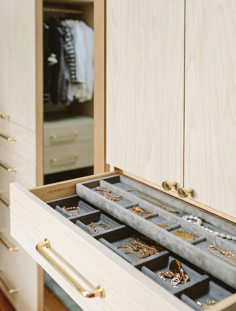 Closet drawer for accessories with gold tone hardware and in a a light wood grain finish by California Closets
