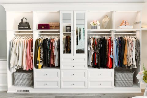 Classic white finish walk in closet with built in drawers, glass doors and high shelves by California Closets