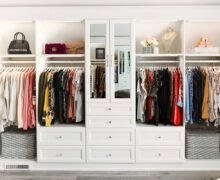 Clásico vestidor con acabado blanco, cajones empotrados, puertas de vidrio y estantes altos de California Closets