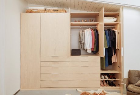 Wardrobe closet with custom cabinets and drawers designed in a natural wood grain finish by California Closets