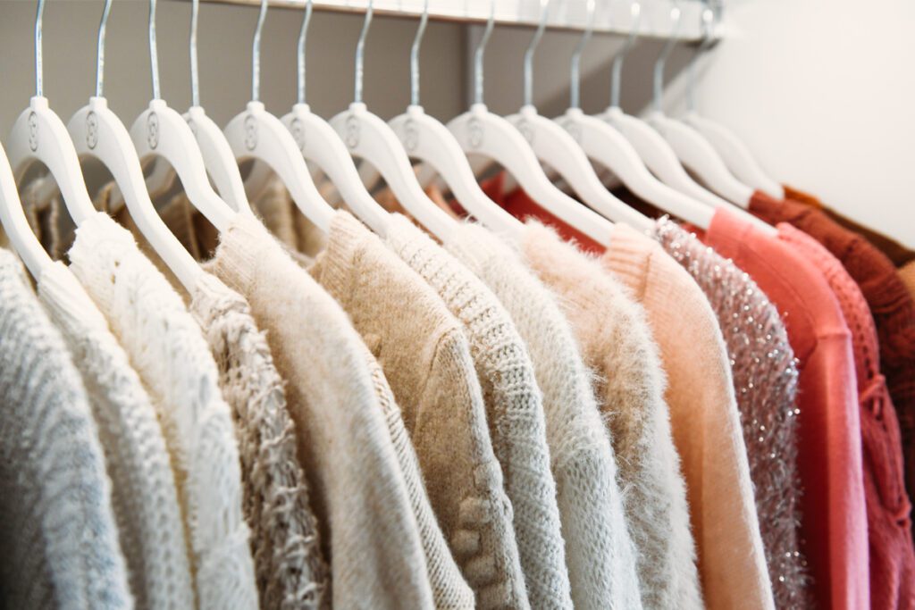 Feng shui organization of sweaters in a custom closet with matching white hangers created by California Closets