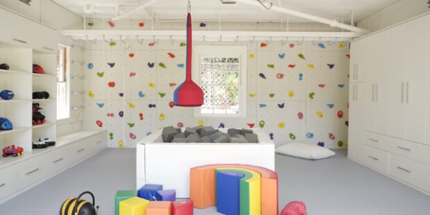 Playroom space with storage after converting a Los Angeles garage for that incorporates a cushy floor, rock climbing wall and extra storage.