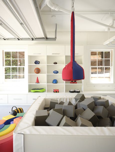 A playroom space with custom built in cabinets and drawers and a foam pit in center for kids in center of space created by California Closets