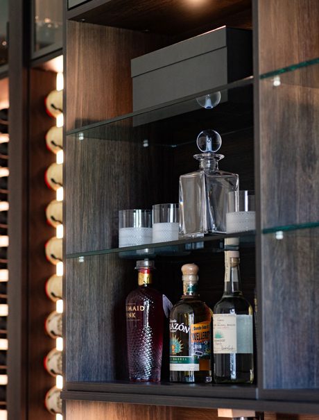 Detail of home wine bar shelving with LED lighting and vertical wine racks designed by California Closets