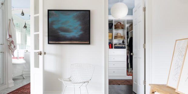 Light and airy walk in closet designed with custom drawers, open shelving, and hanging clothes racks by California Closets