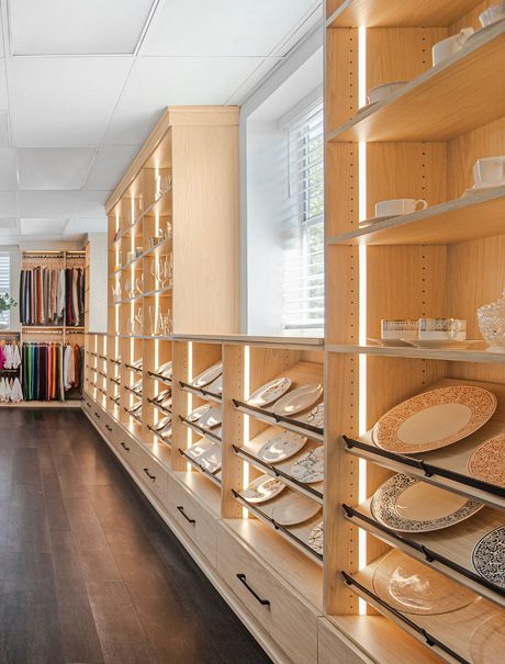 Commercial showroom with open shelving row, illuminated with LED lighting and custom drawers for storage California Closets