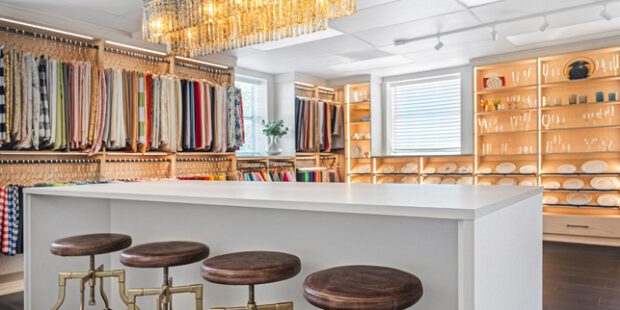 Commercial showroom design with open shelving, hanging poles, LED lighting, custom drawers and storage in natural and linen finishes by California Closets