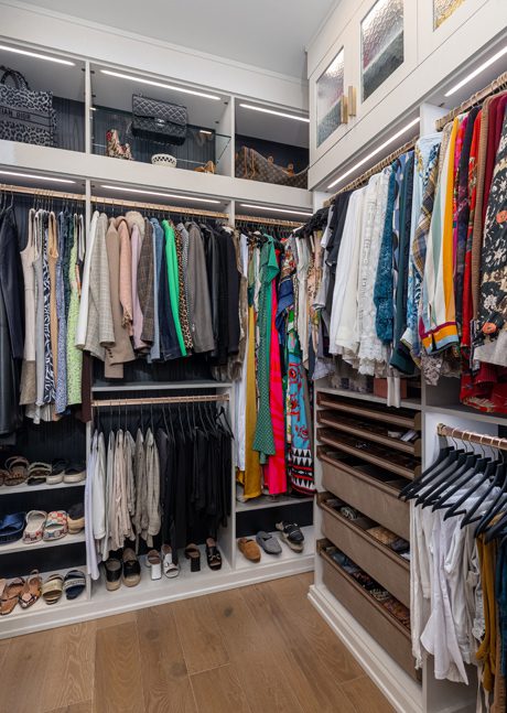 Walk in closet design ideas built out with open shelving, shoe racks, LED lighting and plenty of hanging racks created by California Closets