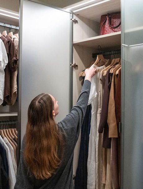 Armario guardarropa con gabinete colgante alto para vestidos largos en acabado de grano de madera con puertas de vidrio creado por California Closets