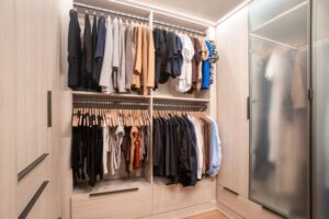 Glass door closet design with wood grain finish and LED lighting created by California Closets